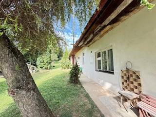Ein Einfamilienhaus in Krivosúd-Bodovka mit traditioneller Fassade, einer Bank und einem Baum im Garten.