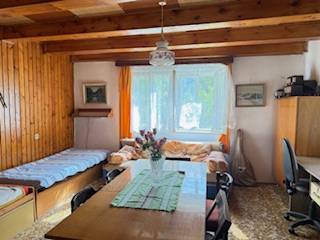 Ein Zimmer in einem Einfamilienhaus mit Holzbalken, einem Esstisch und zwei Betten.