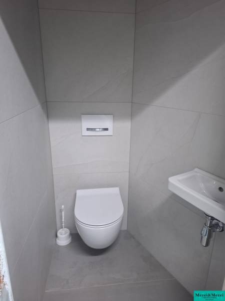 Badezimmer in einem Einfamilienhaus mit Toilette, Waschbecken und weißen Fliesen.