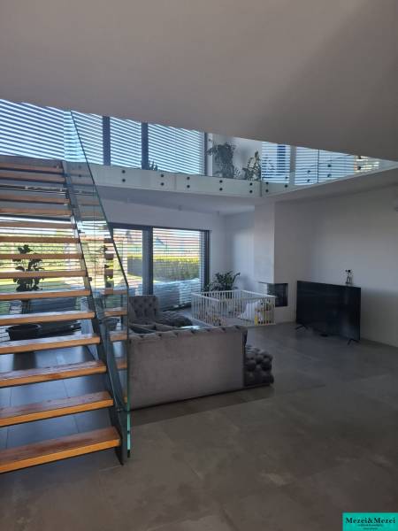 Wohnzimmer in einem Einfamilienhaus mit Treppe und verglasten Geländern.