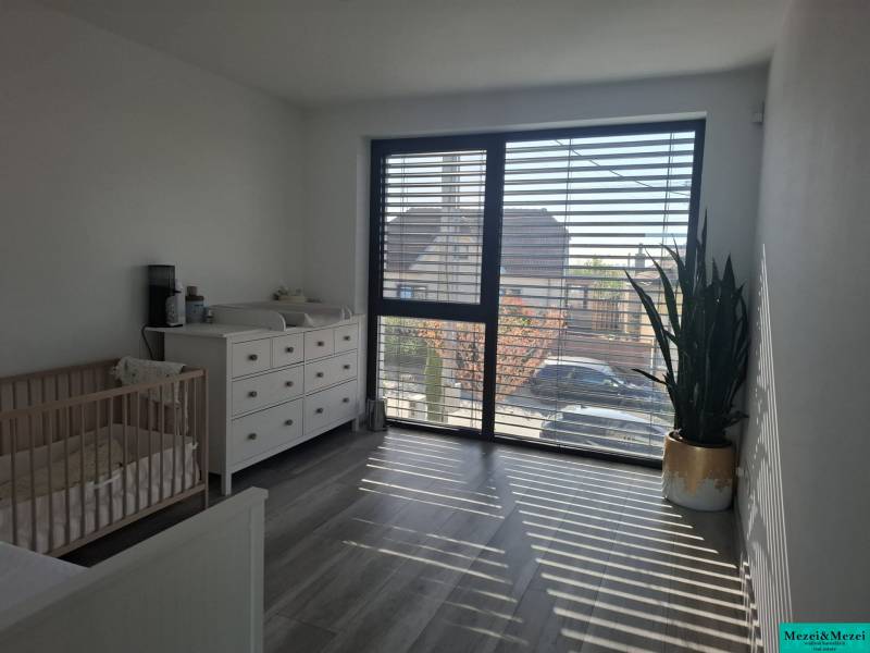 Kinderzimmer in einem Einfamilienhaus mit Kommode, Kinderbett und großem Fenster.