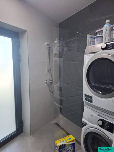 Badezimmer in einem Einfamilienhaus mit Waschmaschine und Duschkabine.