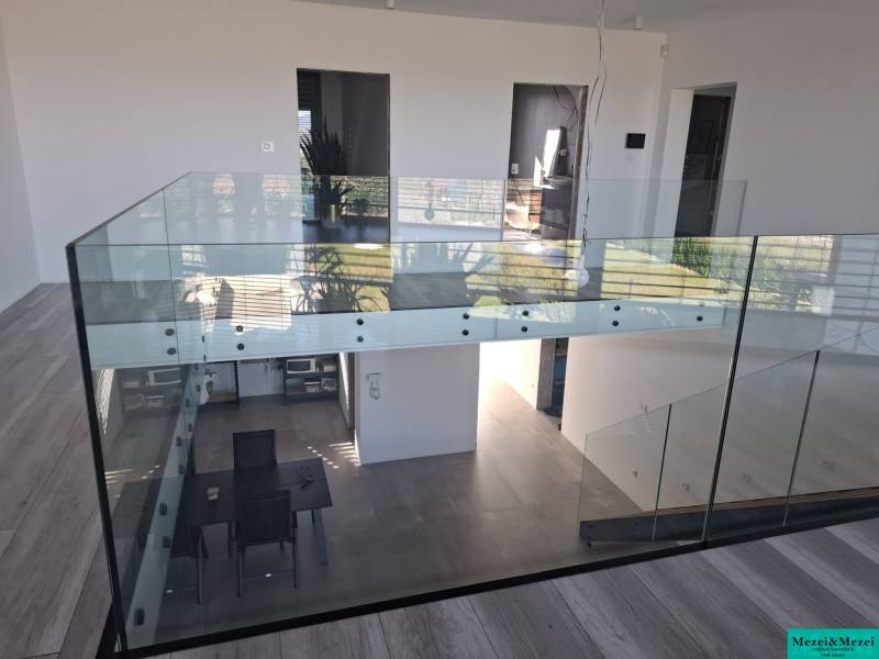 Innenraum eines Einfamilienhauses mit verglastem Geländer und Holzboden.