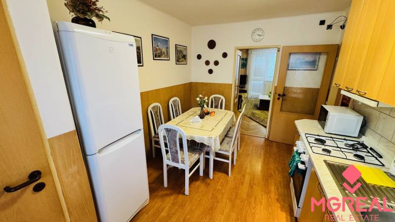 Küche in einer 3-Zimmer-Wohnung mit Esstisch und Boden mit Holzdekor.