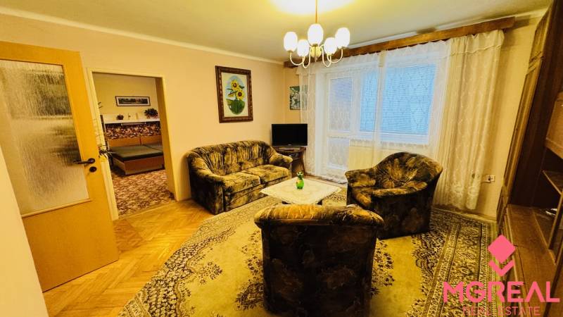 Wohnzimmer in einer 3-Zimmer-Wohnung mit Sofa, Sessel und Holzboden.