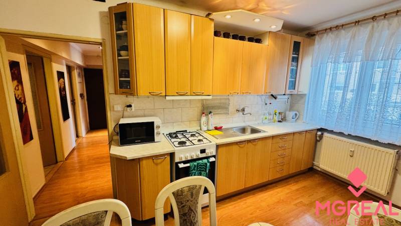 Küche in einer 3-Zimmer-Wohnung mit einer Küchenzeile und einem Boden in Holzoptik.