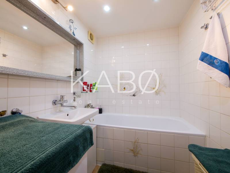 Badezimmer in einer 3-Zimmer-Wohnung mit Badewanne, Waschbecken und weißen Fliesen.