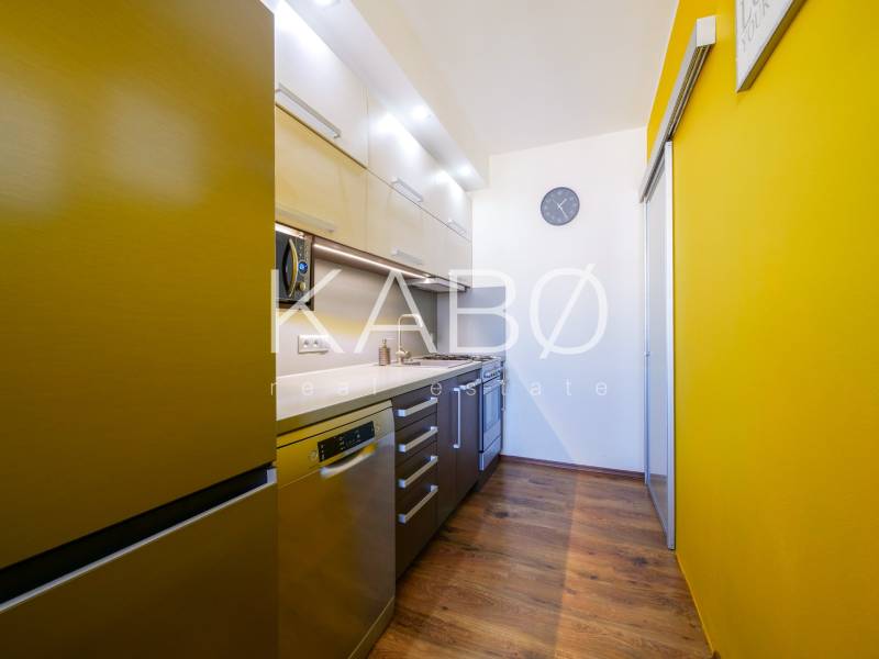 Küche in einer 3-Zimmer-Wohnung mit einer farbigen Wand und einem Boden in Holzoptik.