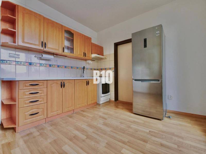 Küche mit Holzschränken und Holzboden in einer 3-Zimmer-Wohnung.