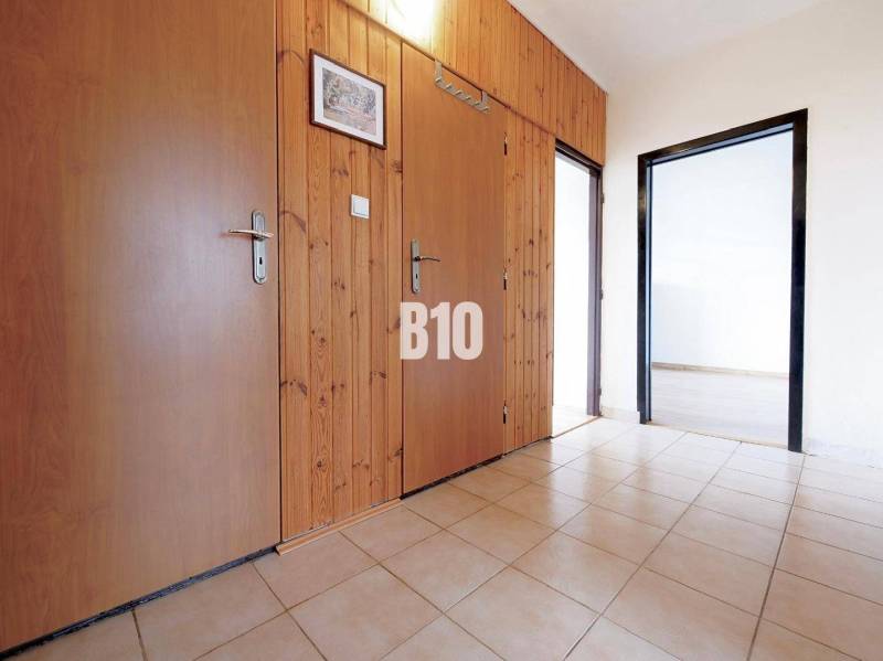 Flur in einer 3-Zimmer-Wohnung mit Fliesenboden, Holzverkleidung und Eingängen zu weiteren Räumen.