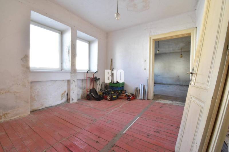 Ein Zimmer in einem Einfamilienhaus mit rotem Boden und Fenstern, Bytča.