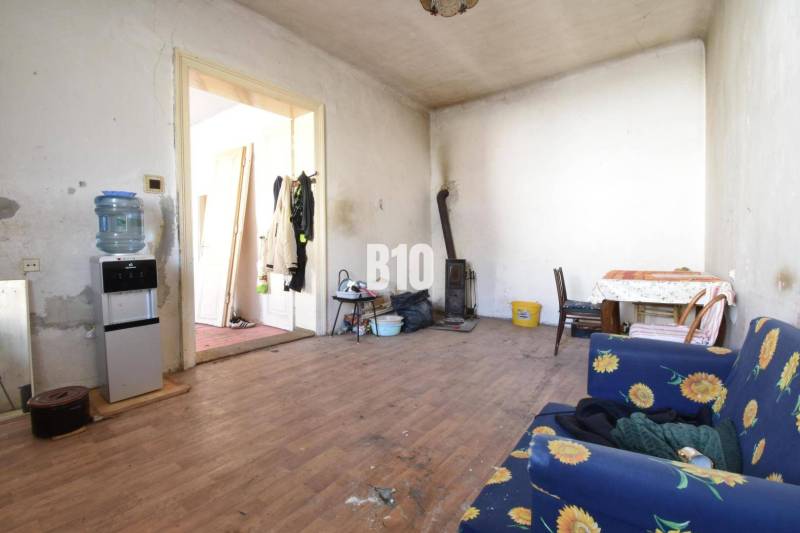 Ein Zimmer in einem Einfamilienhaus mit einem Holzboden, einem Ofen und Möbeln mit Blumenstoff.