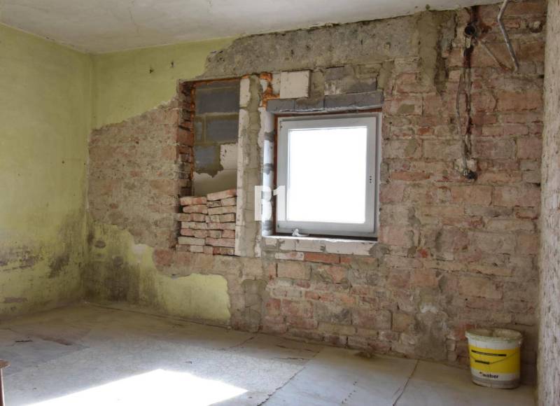 Ein Zimmer in einem Einfamilienhaus mit Ziegelwänden und einem Eimer auf dem Boden.