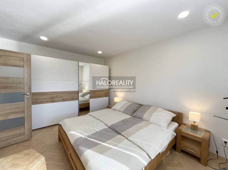 Schlafzimmer mit Holzboden in einer Einzimmerwohnung, helles Bett und Kleiderschrank.