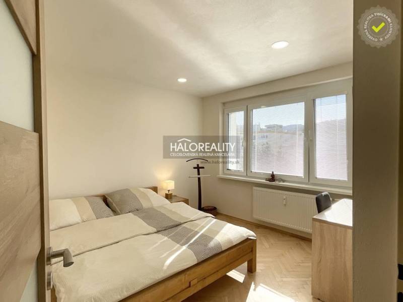 Schlafzimmer in einer Einzimmerwohnung mit Holzboden und großen Fenstern.