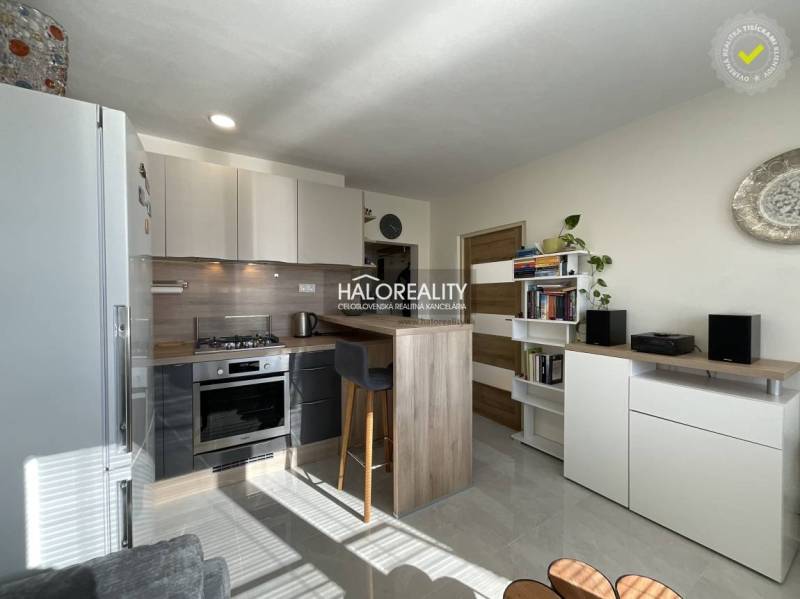 Küche in einer Einzimmerwohnung mit hellem Interieur und einer Theke zum Sitzen.