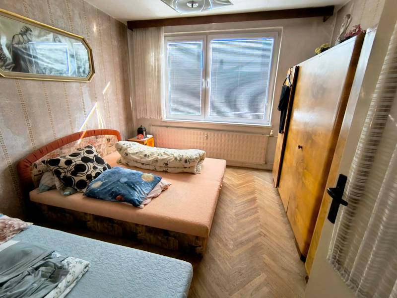 Schlafzimmer in einer 3-Zimmer-Wohnung mit Bett, Schrank und Boden in Holzoptik.