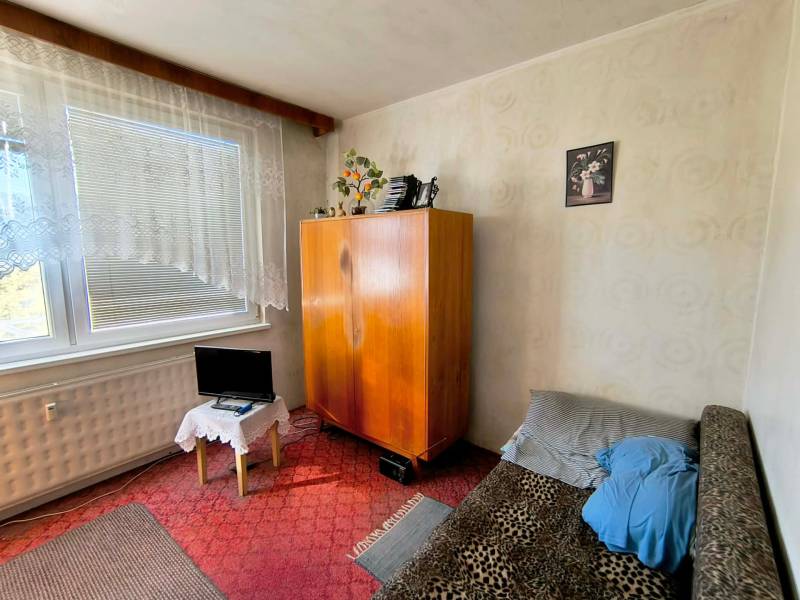 Ein Zimmer in einer 3-Zimmer-Wohnung mit einem Schrank, einem Sofa und einem kleinen Bildschirm.