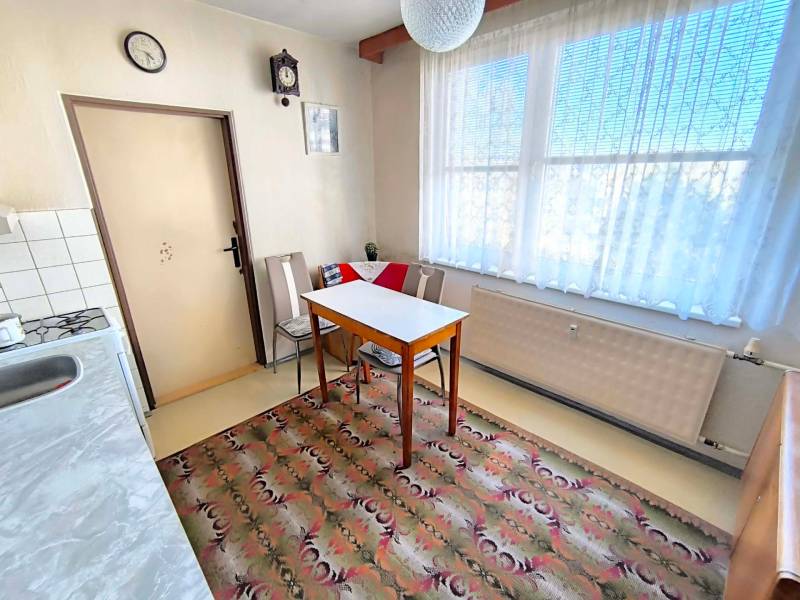 Küche in einer 3-Zimmer-Wohnung mit Esstisch, Stühlen und Teppich.