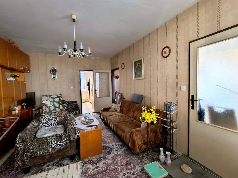 Wohnzimmer in einer 3-Zimmer-Wohnung mit Sesseln, Blumen und einem Vintage-Kronleuchter.