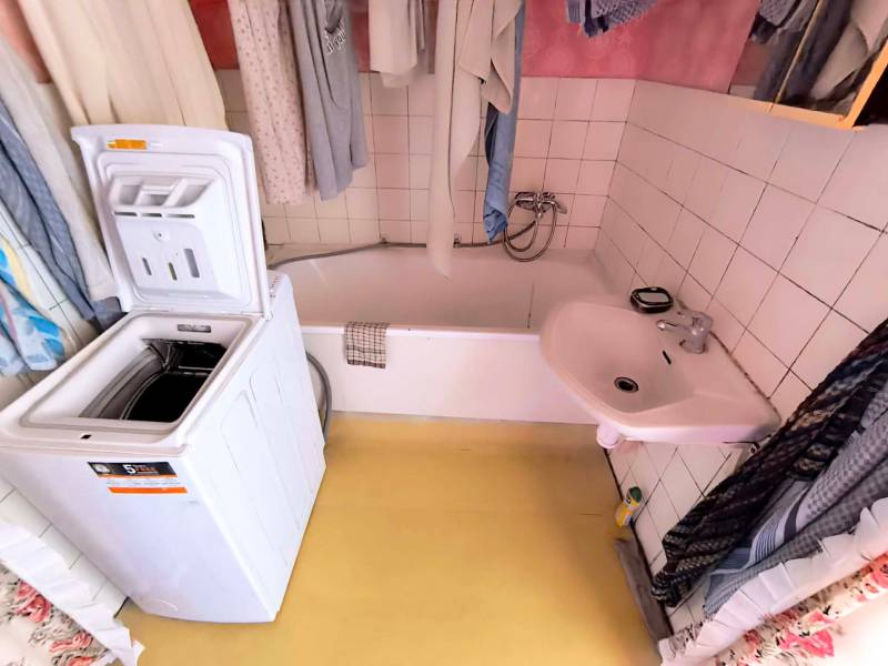 Badezimmer mit Waschbecken, Badewanne und Waschmaschine in einer 3-Zimmer-Wohnung.