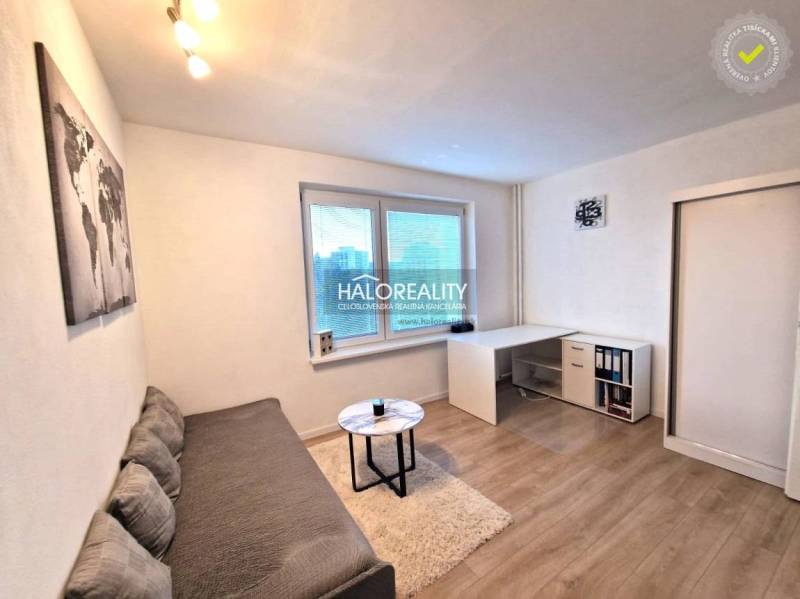 Wohnzimmer in einer 3-Zimmer-Wohnung mit Sofa, Tisch und Holzboden.