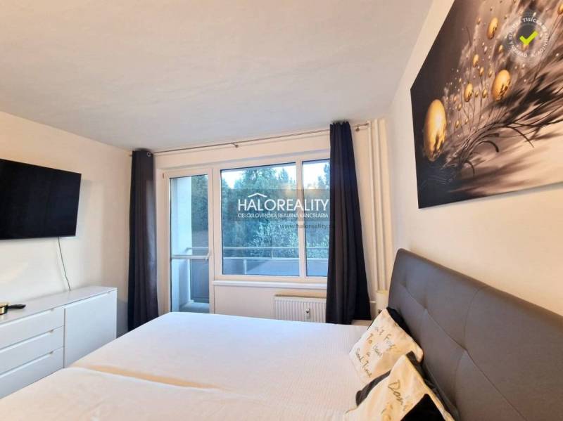 Schlafzimmer in einer 3-Zimmer-Wohnung mit großem Bett, Fernseher und Balkon.