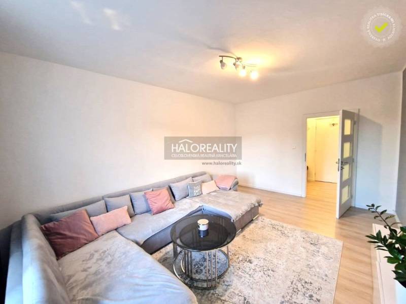 Wohnzimmer in einer 3-Zimmer-Wohnung mit einem großen Ecksofa und einem Boden in Holzoptik.