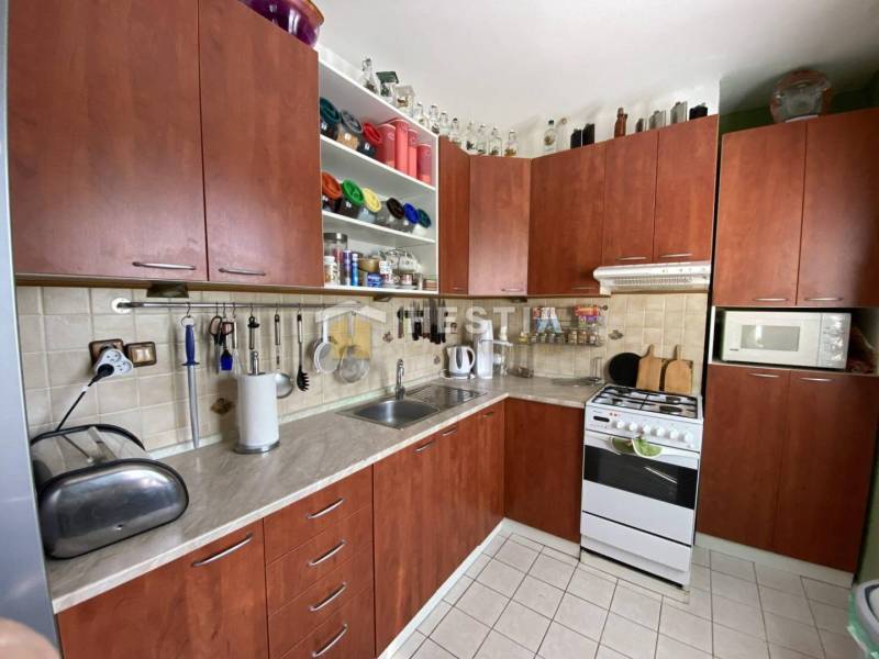 Küche in einer 2-Zimmer-Wohnung mit Holzschränken und weißen Fliesen.