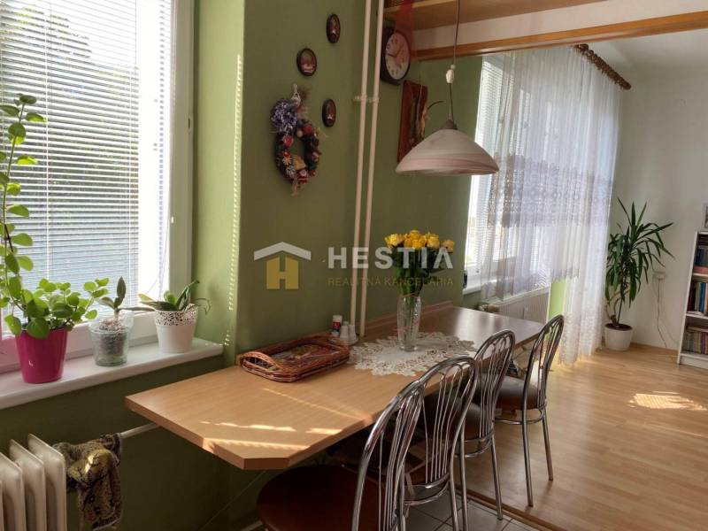 Esszimmer mit Holzelementen, grünen Wänden, Blumen und einem Tisch in einer 2-Zimmer-Wohnung.