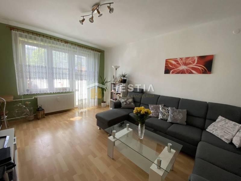 Wohnzimmer mit bequemer Couch, Glastisch und Holzboden in einer 2-Zimmer-Wohnung.