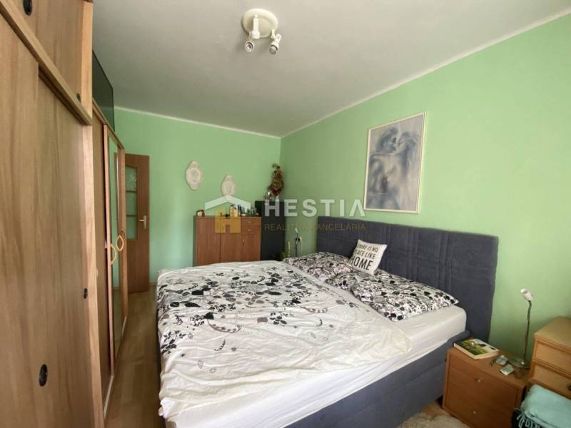 Schlafzimmer in einer 2-Zimmer-Wohnung mit Bett und Möbeln, die Wände sind hellgrün.