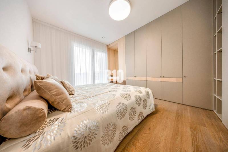 Schlafzimmer in einer 3-Zimmer-Wohnung mit Bett, Einbauschrank und Boden in Holzoptik.