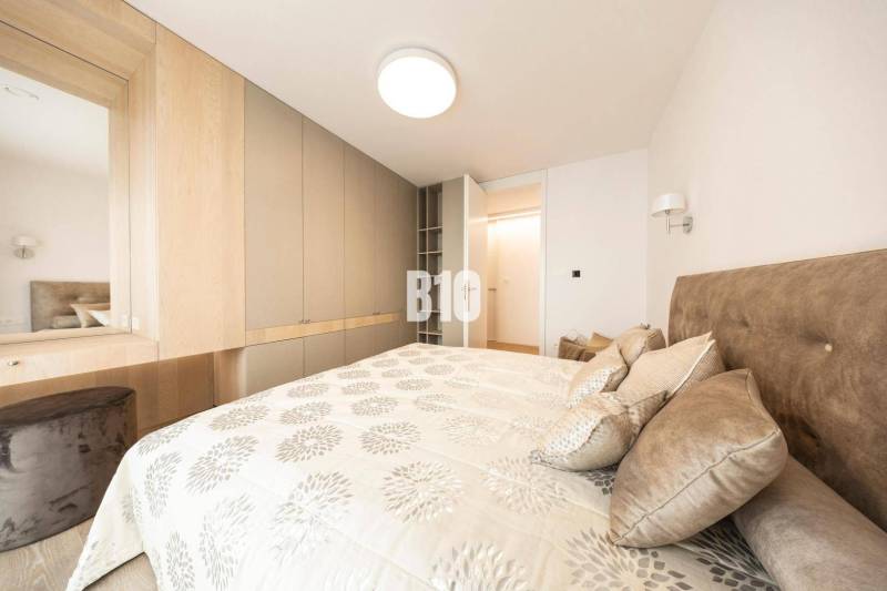 Schlafzimmer in einer 3-Zimmer-Wohnung mit Stauraum und einem Bett mit gemusterten Textilien.