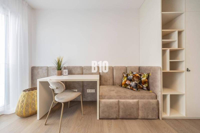 Arbeitsbereich mit Stuhl, Tisch, Bank und Regalen in einer 3-Zimmer-Wohnung.