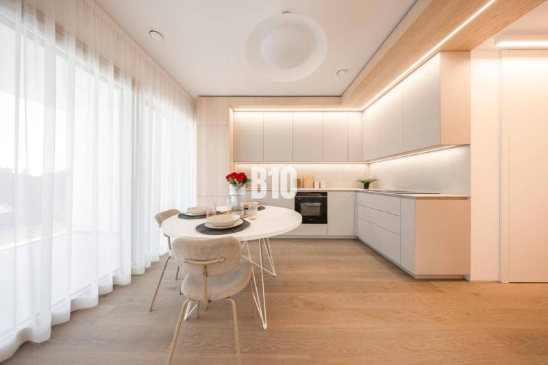 Küche in einer 3-Zimmer-Wohnung mit weißen Möbeln und einem Boden in Holzoptik.