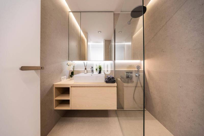 Badezimmer mit Spiegel, Dusche und Holzelementen in einer 3-Zimmer-Wohnung.