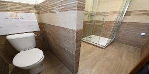 Badezimmer in einer 2-Zimmer-Wohnung mit Toilette und Fliesen in Holzoptik.