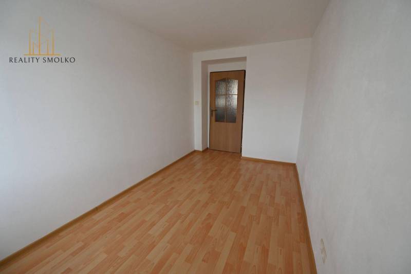 Ein Zimmer in einer 2-Zimmer-Wohnung mit einem Boden in Holzoptik und weißen Wänden.