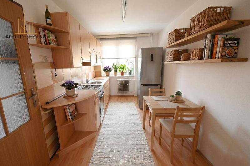 Küche in einer 2-Zimmer-Wohnung mit Holzboden, Esstisch und Regale.