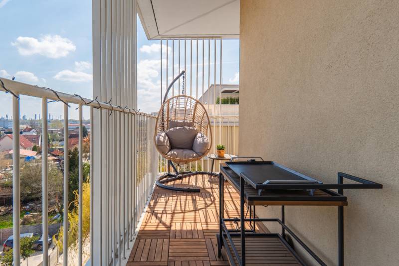 Der Balkon einer 3-Zimmer-Wohnung in Bratislava-Ružinov mit einer Schaukel und Blick auf die Stadt.