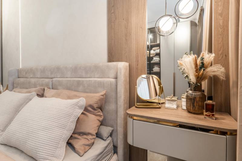 Schlafzimmer in einer 3-Zimmer-Wohnung mit Bett, Spiegel und dekorativen Elementen.