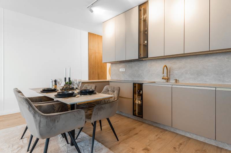 Küche in einer 3-Zimmer-Wohnung mit Esstisch und Boden in Holzoptik.