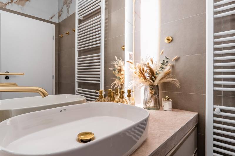 Badezimmer mit goldenen Details und Dekoration in einer 3-Zimmer-Wohnung.