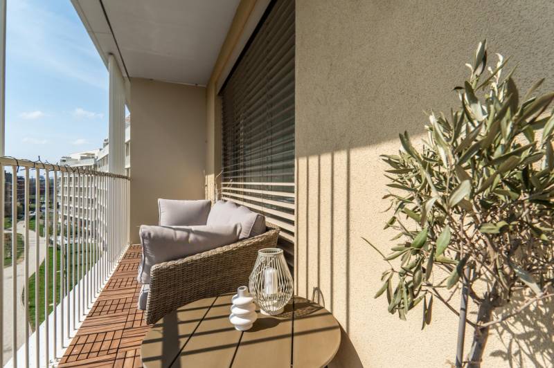 Ein Balkon in einer 3-Zimmer-Wohnung mit bequemen Sitzgelegenheiten, Aussicht und Dekorationen.