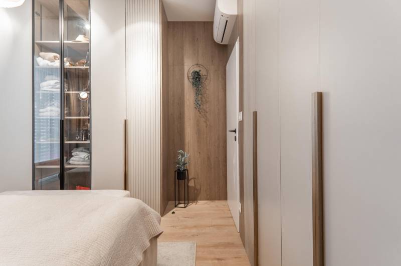 Gemütliches Schlafzimmer mit Holzboden und Glasschrank in einer 3-Zimmer-Wohnung.