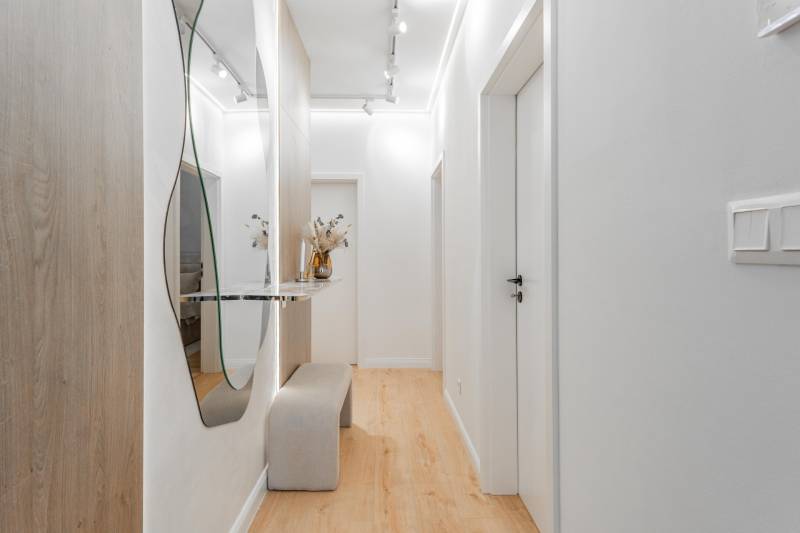 Ein heller Flur mit Spiegel, Bank und Boden in Holzoptik in einer 3-Zimmer-Wohnung.
