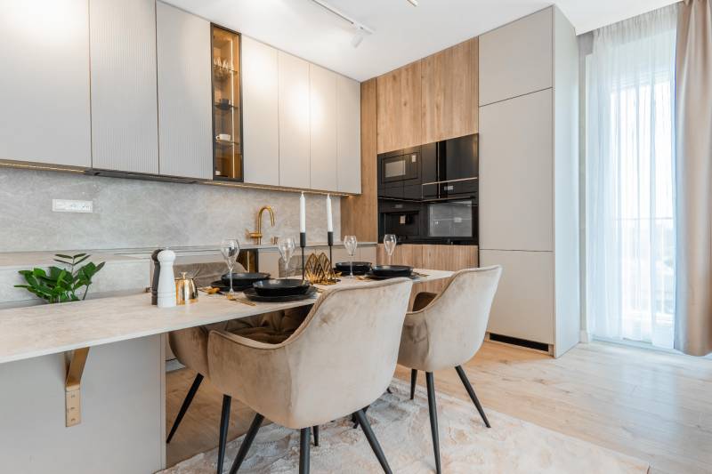 Stilvolle Küche in einer 3-Zimmer-Wohnung mit Esstisch und Boden in Holzoptik.