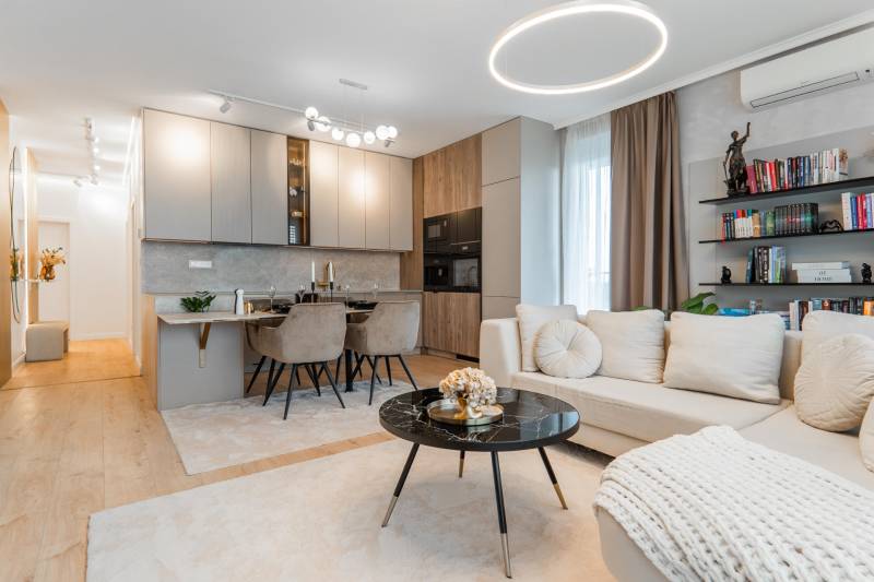 Ein stilvolles Wohnzimmer mit Küche in einer 3-Zimmer-Wohnung, helle Farbtöne, Boden mit Holzdekor.