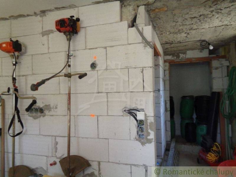 Innenraum eines Einfamilienhauses mit Werkzeug an der Wand und Lagertonnen in Šiatorská Bukovinka.